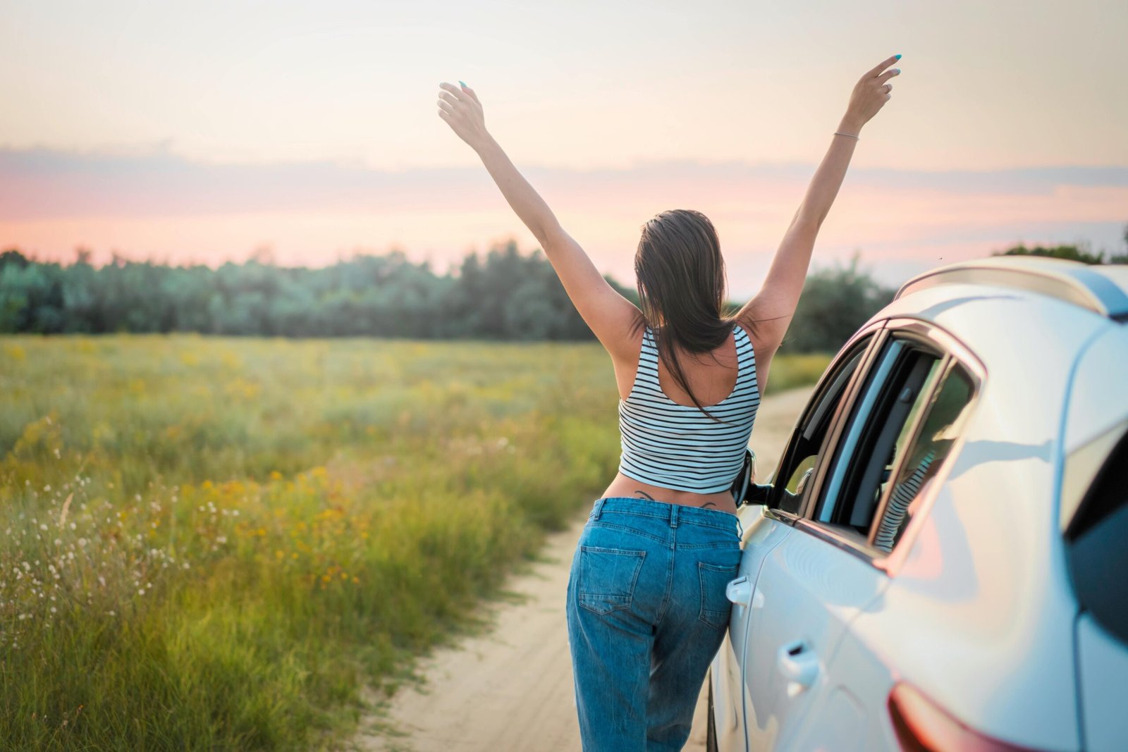 Woman leaning on her car and celebrating joyfully, symbolizing confidence, achievement, and empowerment