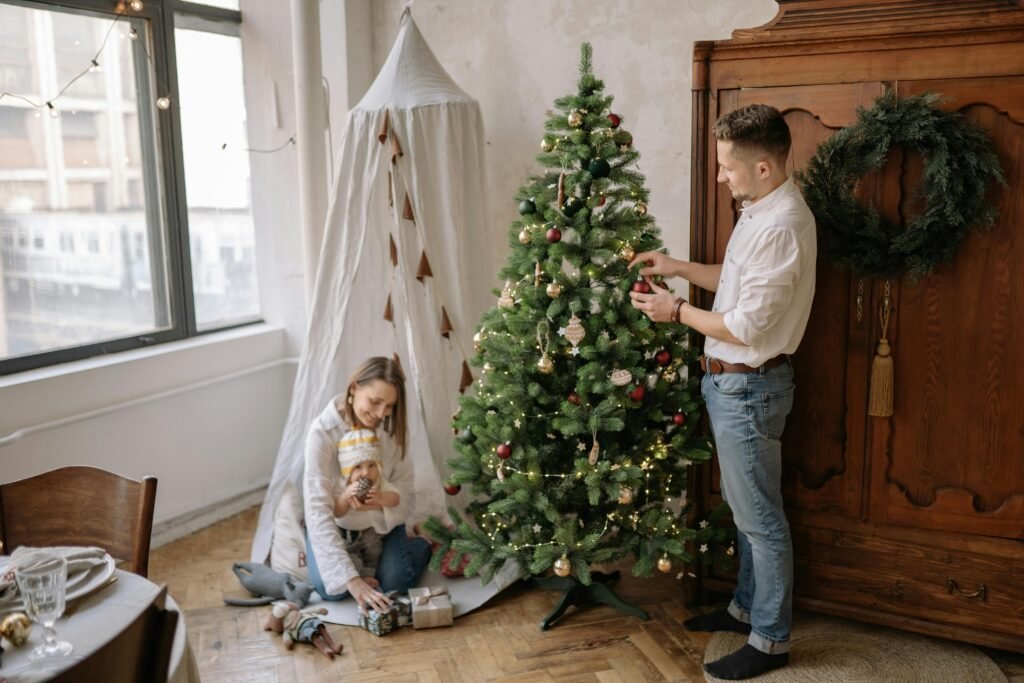 Mother holding baby in her lap while decorating for Christmas celebration, creating a warm festive moment