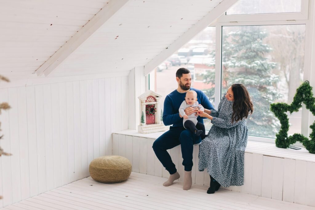 Father keeping baby in lap with mother sitting nearby, reflecting family bonding and care