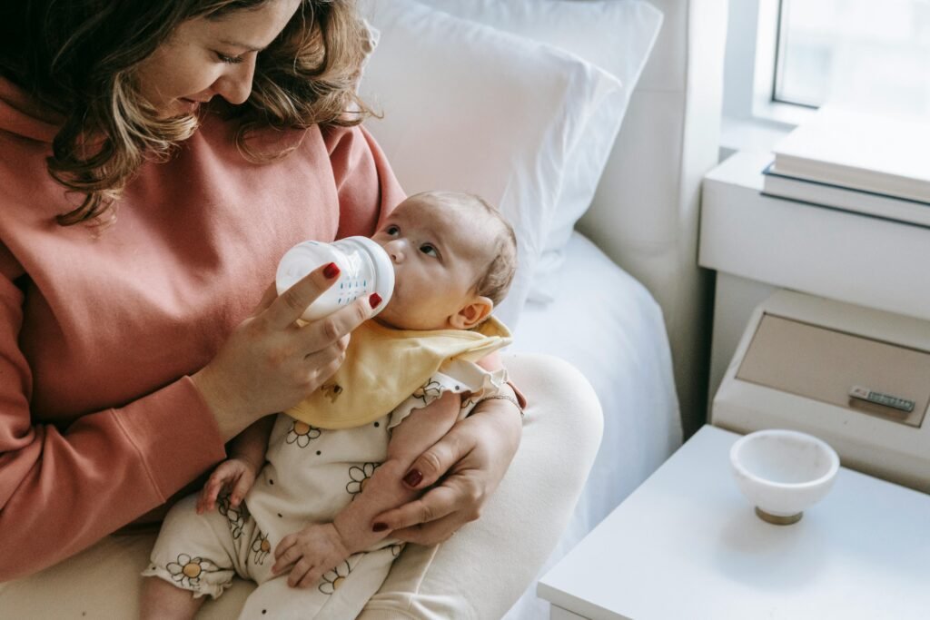 Mother feeding milk in a sipper to her newborn, showing care, nourishment, and tenderness